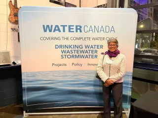 Attendee standing beside a Water Canada event backdrop