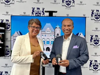 Two people exchanging an award in front of an event backdrop